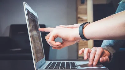two sets of hands on laptop computer discussing what is on the screen